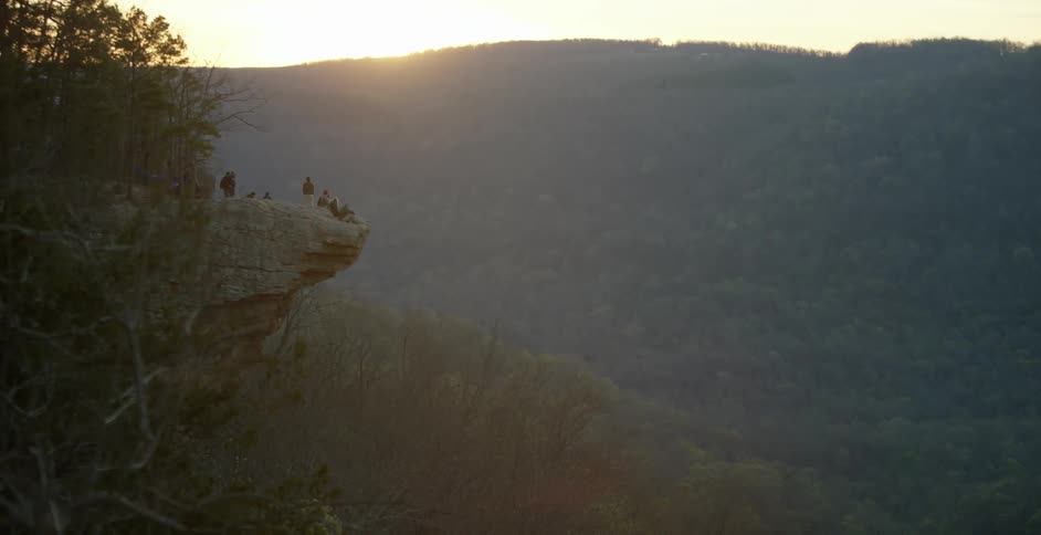 Sun setting behind a tree covered mountain