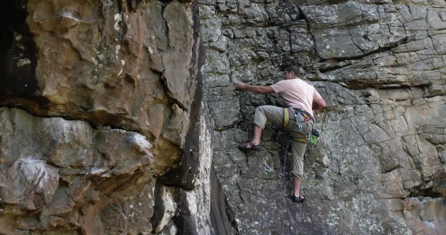A man climbs up a rocky cliffside
