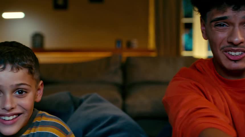 Two boys sitting in the living room having fun playing video games