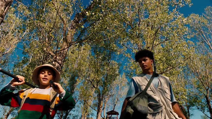 Two boys with fishing gear walking in a wooded area