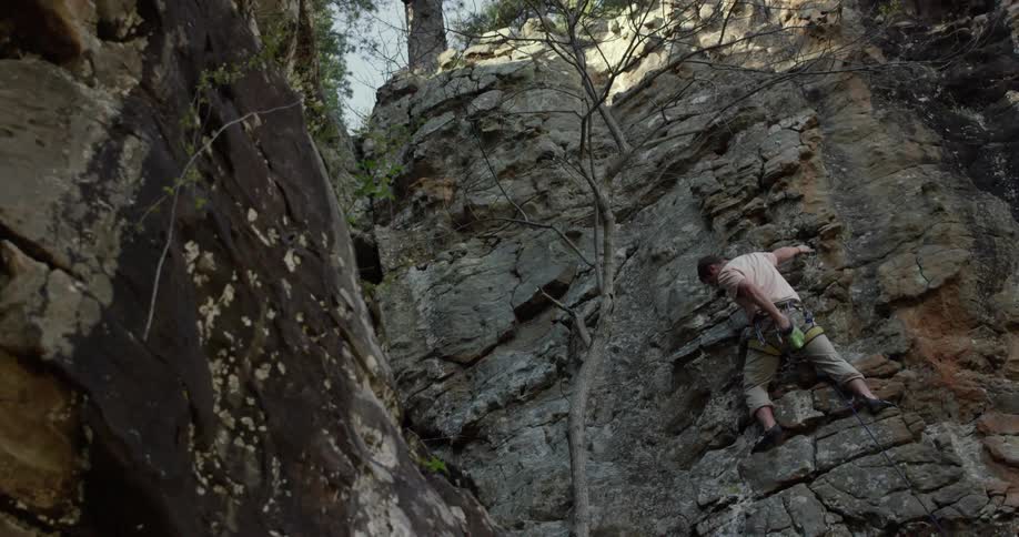 A man reaches into a chalk bag while rock climbing