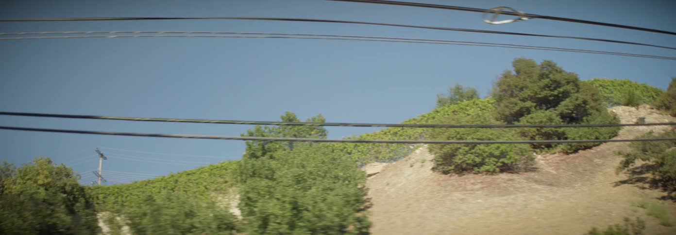 Car driving along a road on the edge of a hill with power cables