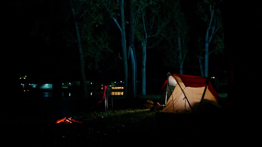 Boy laying down in a camping tent and turning off the light
