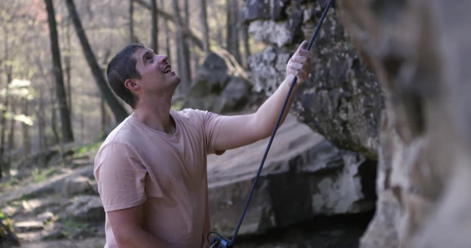 A guy pulling on a rope next to a cliff