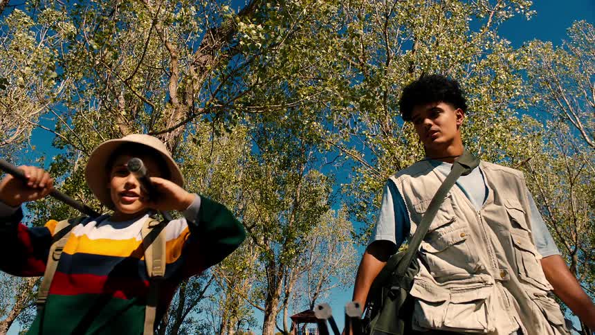 Two brothers carry gear while walking through a forest