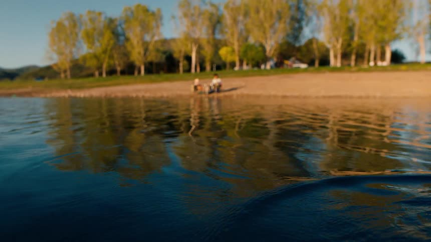 Fish float sinks when a fish takes the bait while two people fish on a sunny summer day