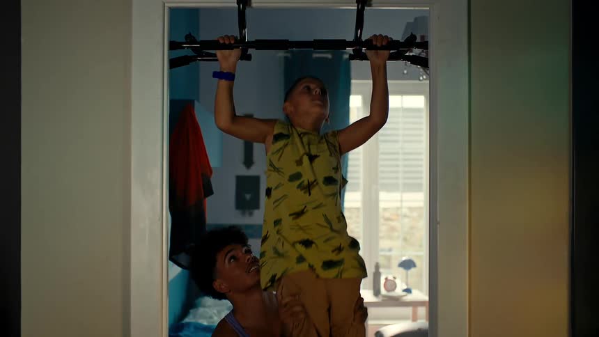 A child is doing pull ups with help