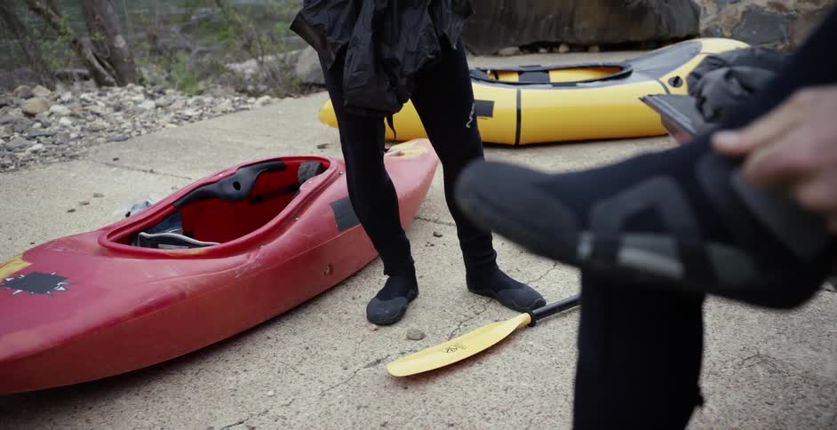 A man is adjusting his wetsuit over his water shoes