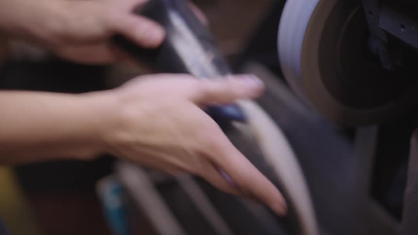 Close up of hands holding a leather shoe and shaping the sole