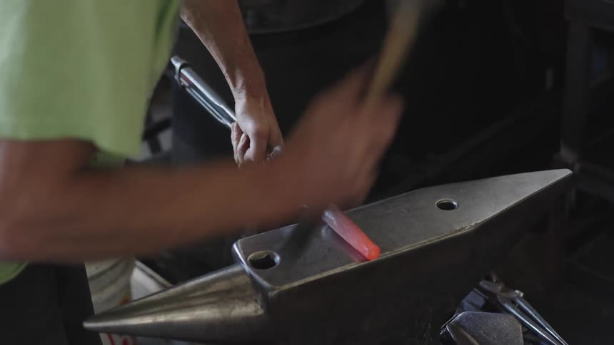 The blacksmith carefully shapes the redhot metal using a hammer and anvil to forge it into a desired shape