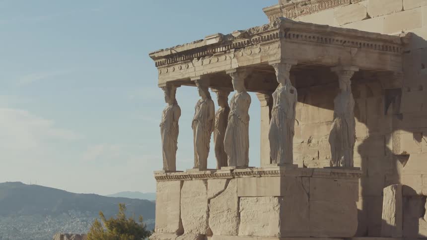 An ancient crumbling building sporting statues used as pillars to hold up the roof