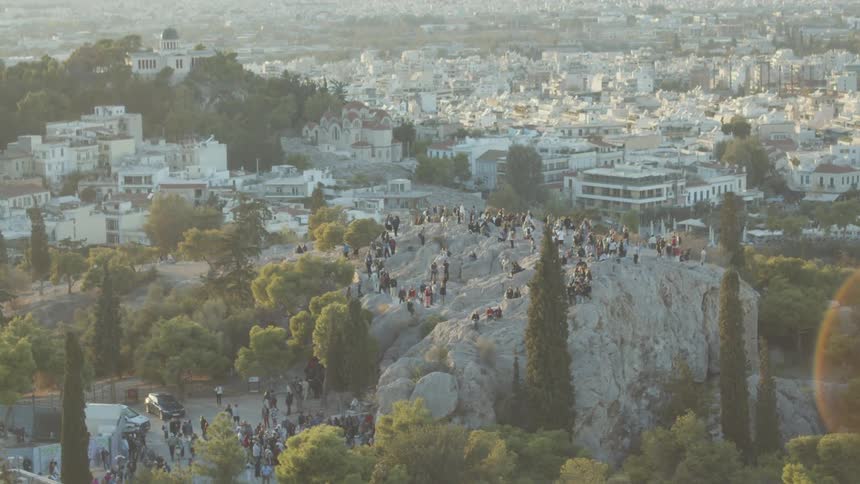 Crowd on top of a rocky hill on a mountain surrounded by a city urban