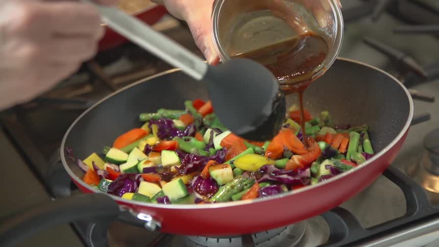 Sauce is poured into a skillet of vegetables