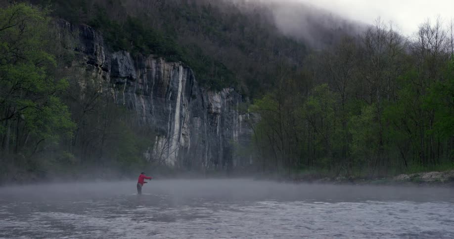 A man stands in the water while fishing