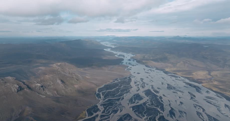 A winding river flows through a vast barren landscape with mountains in the distance