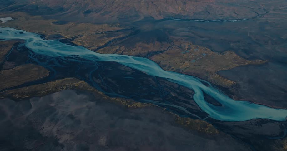 Aerial view of a winding river with multiple branches flowing through an arid landscape with varying shades of brown and blue