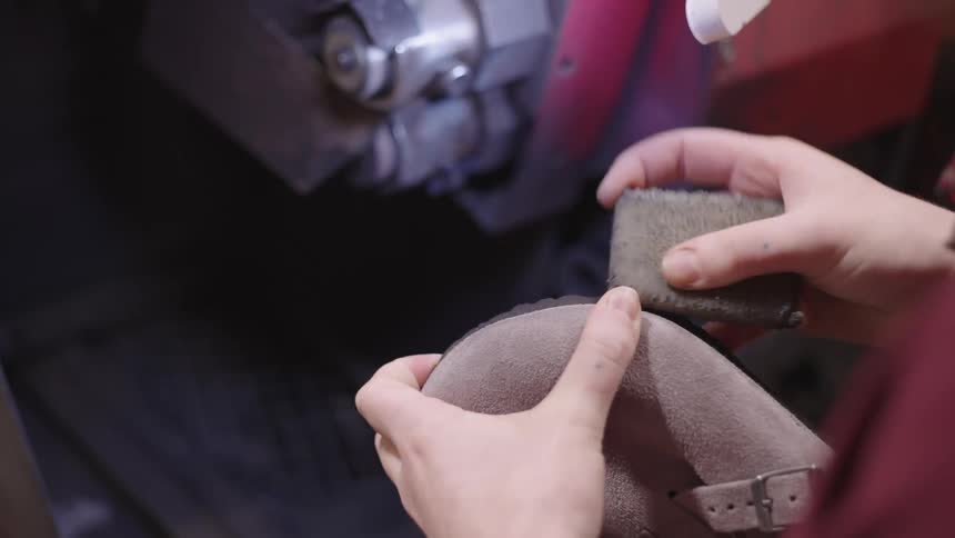 A person buffs a suede shoe with a cloth