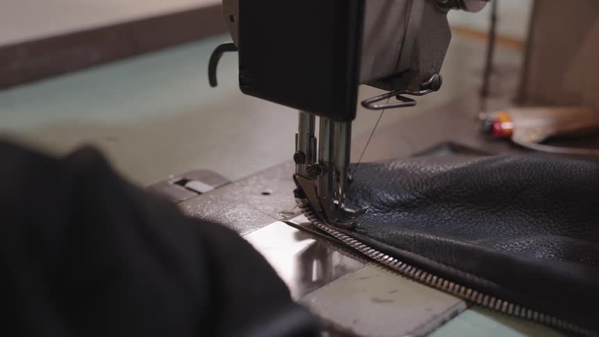 Close up of a womans hand sewing on a machine