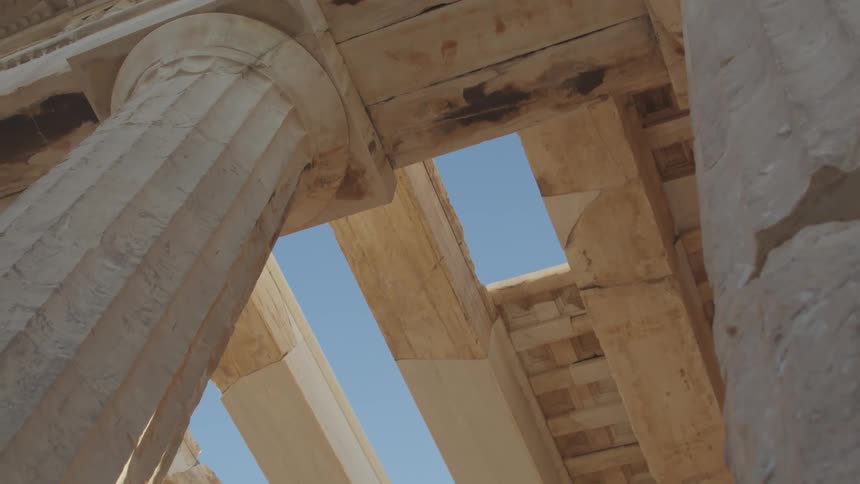 A view up the columns of a classical greek temple with a patch of blue sky visible above