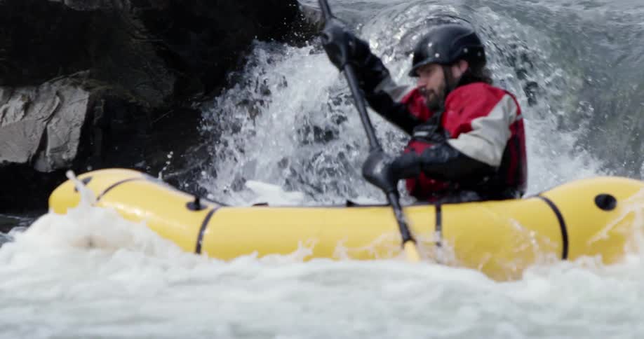A kayaker is navigating rapids during the day