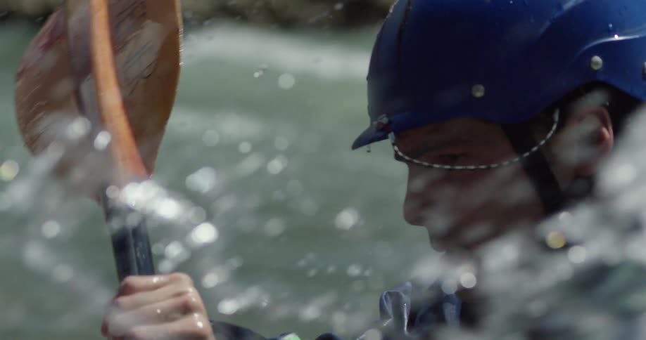 Water splashes up as a man rows against the river current