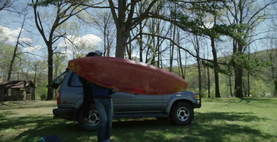 People removing a kayak from the top of their vehicle