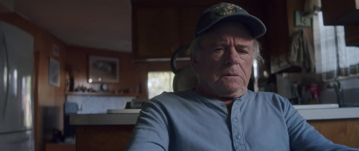 Elderly man sitting in kitchen and reading letters