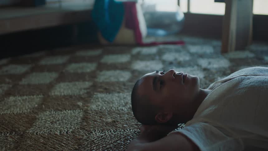 Young man lying on carpet in thought