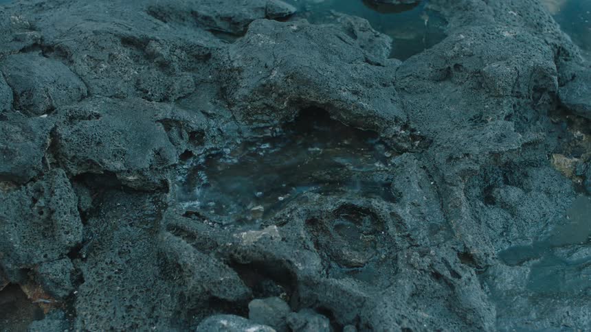 Bare foot of a person stepping into a puddle of water on a rock