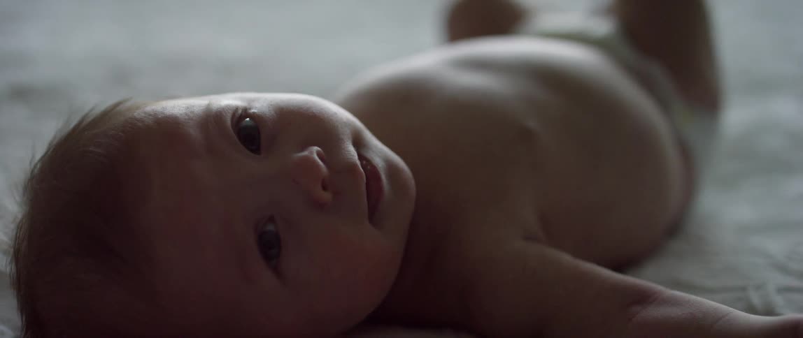 A baby laying on it's back and looking at the camera