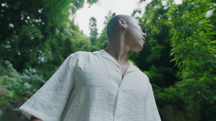 Man taking off a scarf while standing in a forest setting