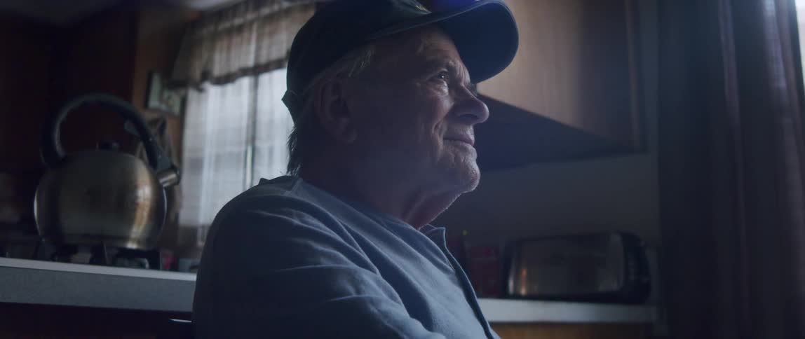 Elderly man sitting giving an emotional smile