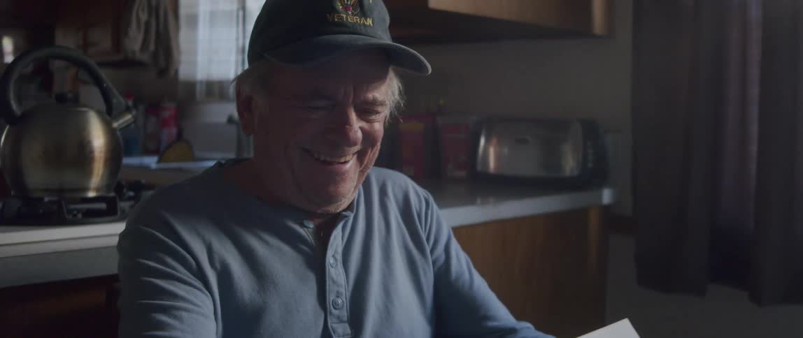 An elderly man looks happy as he reads a letter