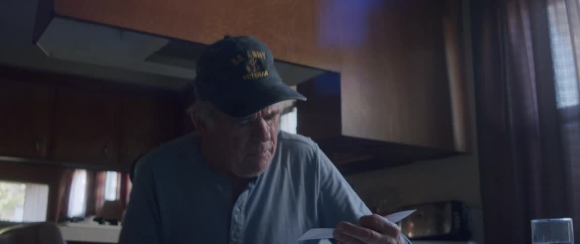 Elderly man with cards in hand sitting at the table