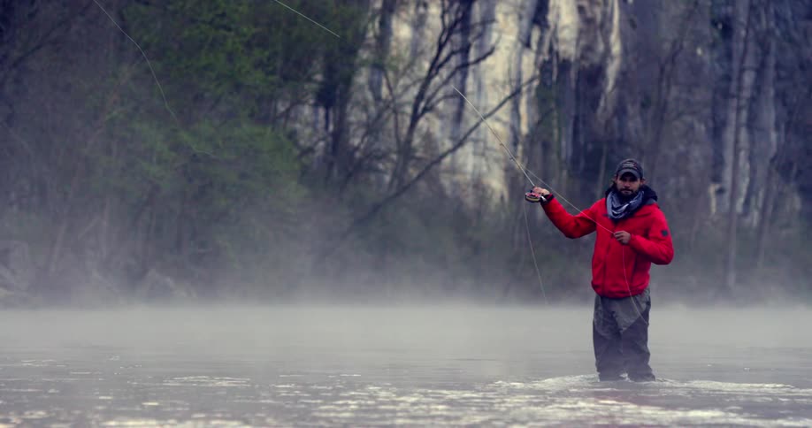 Man fly fishing with mist all around him