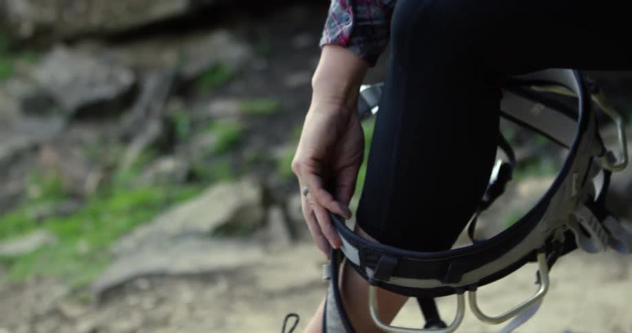 A woman puts her legs into a harness