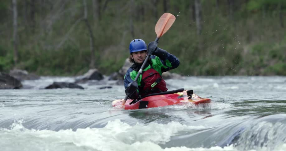 A man paddling a kayak in rapidly moving water