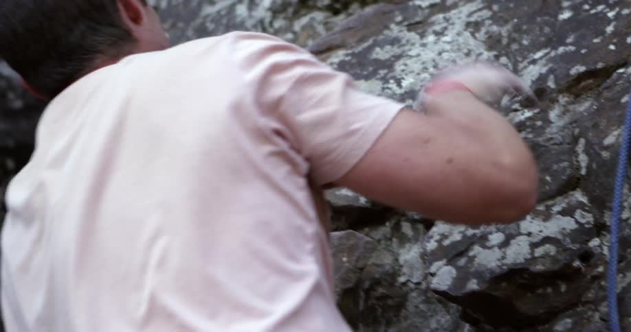 Rock climber reaching to pull himself up even higher