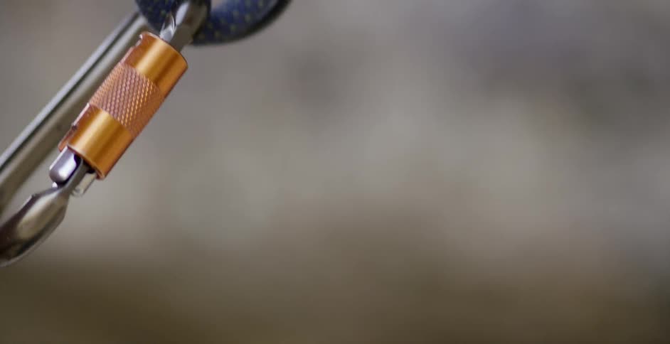 A rock climber tightens a rope on a clip