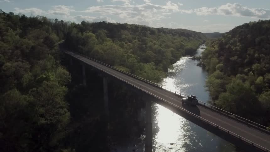 An overhead view of a bridge over water that is surrounded by trees