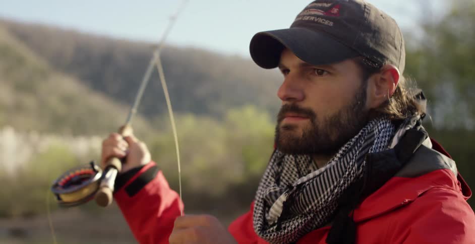 Man going fly fishing in a tree lined lake