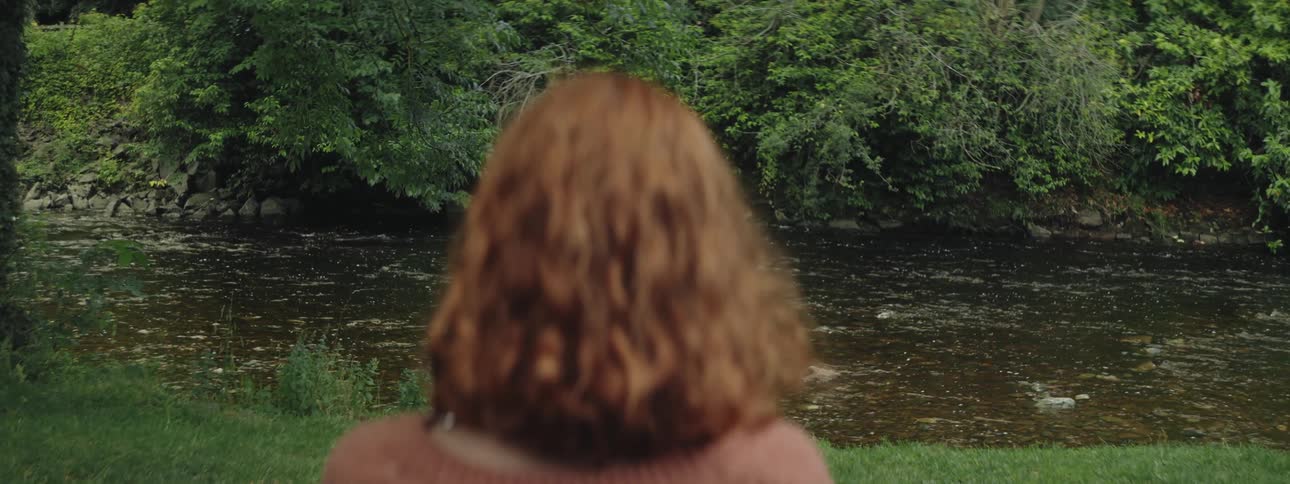 Redheaded woman with her back facing a river