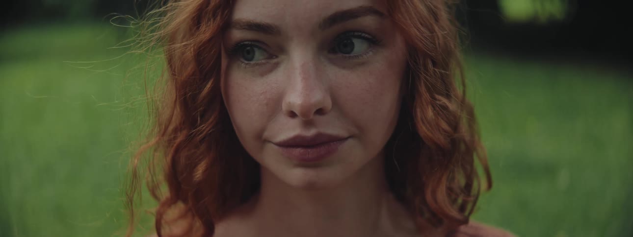 Portrait of a young redhaired woman in an outdoor space with blurred background