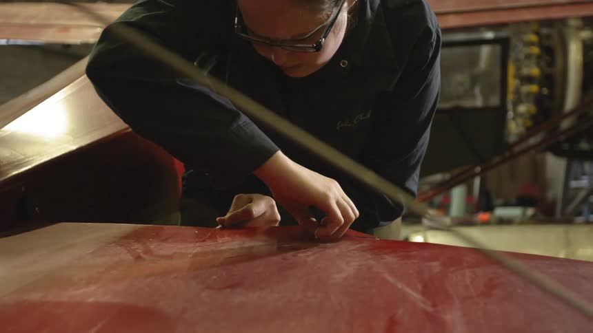 A man uses a razor to cut a red surface