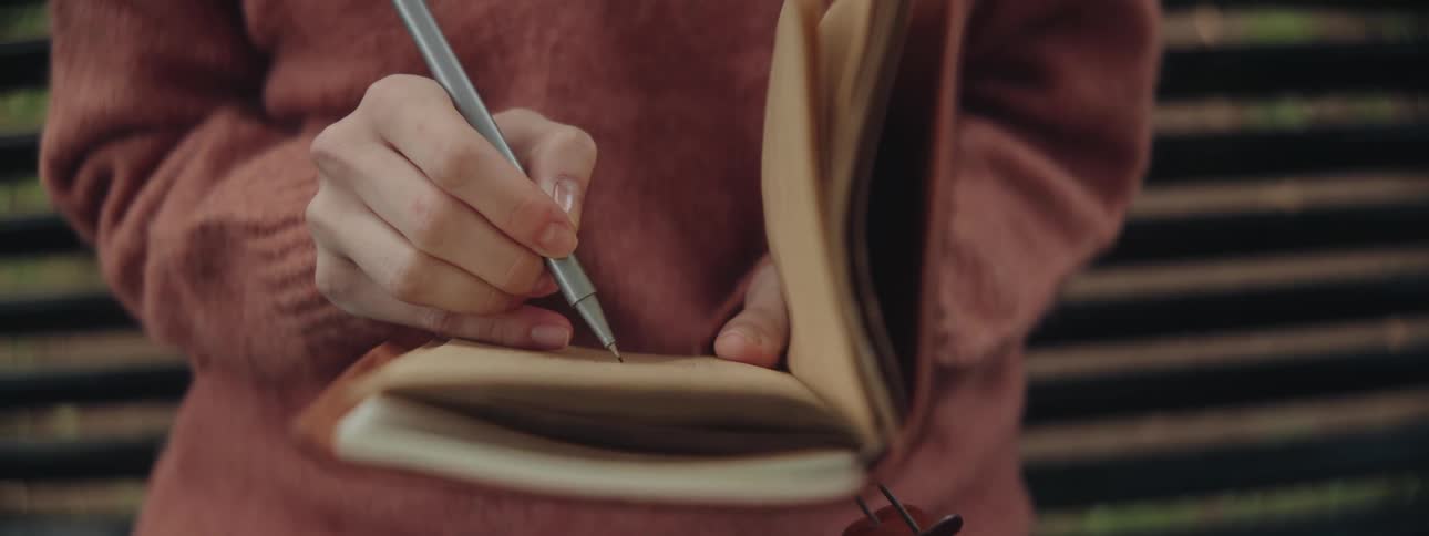 Close up of a hand writing in a book with a pen