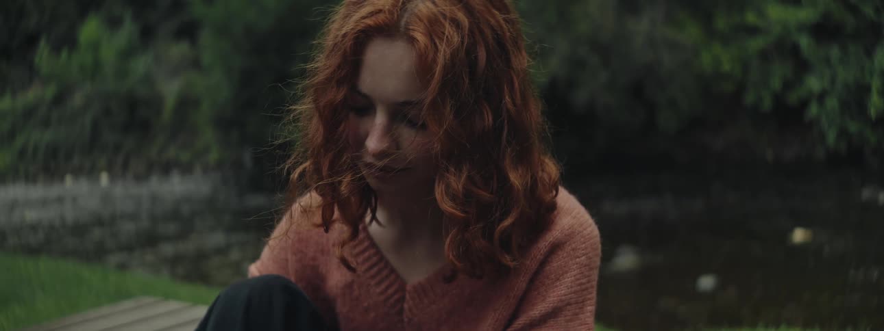 Young woman sitting in a natural setting next to a river