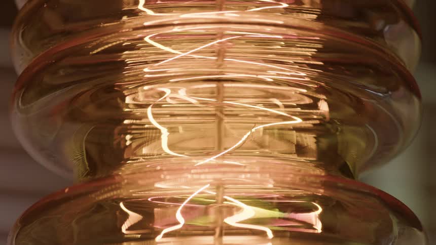 A closeup of an illuminated decorative light bulb with a unique layered shape