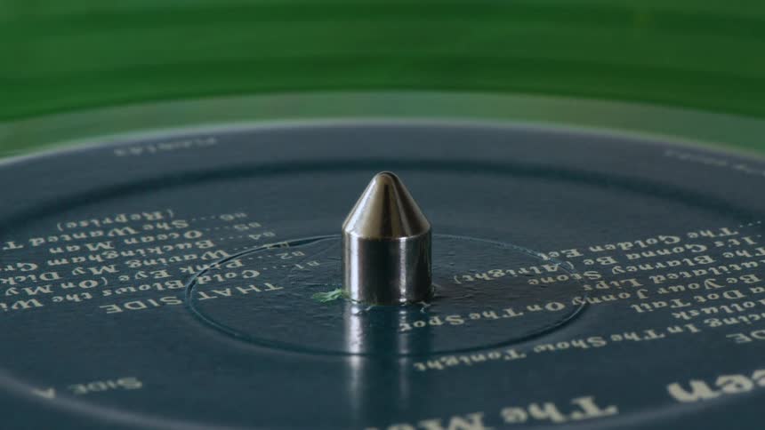 A green vinyl record spins and stops on a turntable