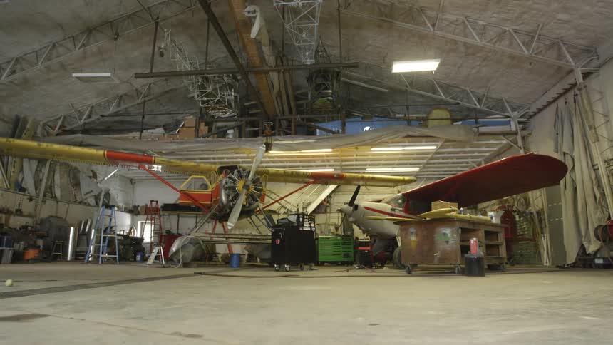 Small airplanes are parked in a hangar