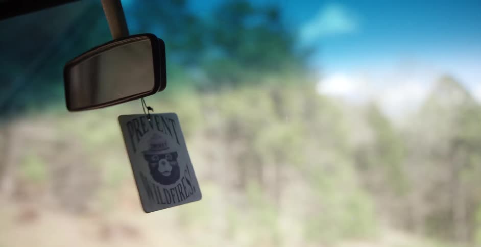 Small sign hanging from a moving rearview mirror